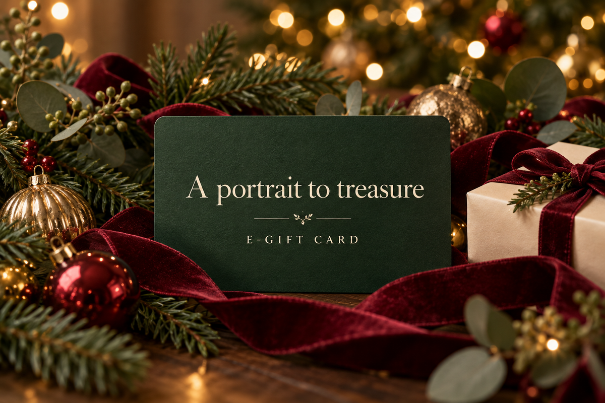 A portrait to treasure e-gift card surrounded by evergreen branches, maroon velvet ribbons and warm Christmas lights.